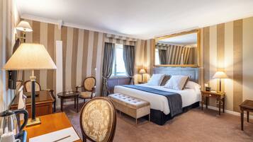 Habitación de hotel con una cama grande, mesitas de noche con lámparas, un escritorio con una silla, una pequeña mesa con una silla y un espejo grande en la pared.