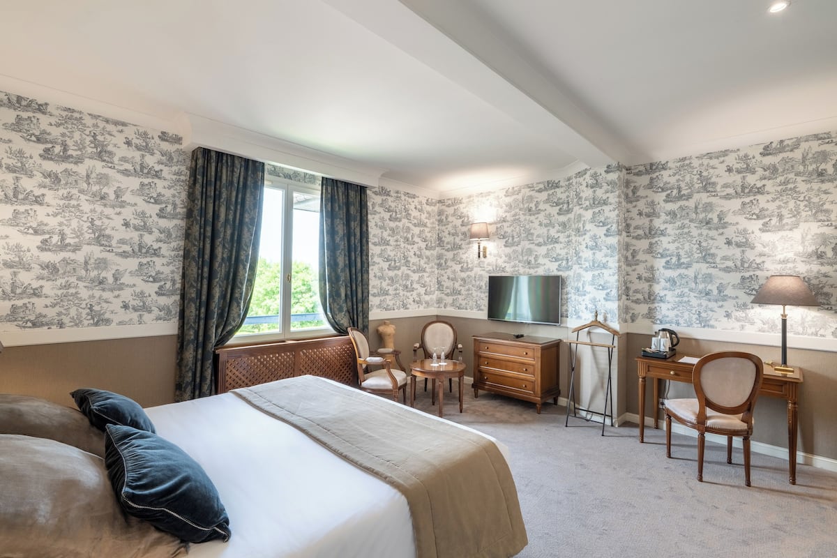 Une chambre d’hôtel avec un grand lit, un bureau, une chaise, une télévision et une lampe.