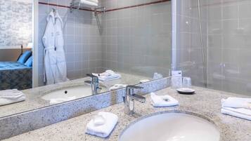 A modern bathroom with a granite countertop, a large mirror, a sink, and a shower area.