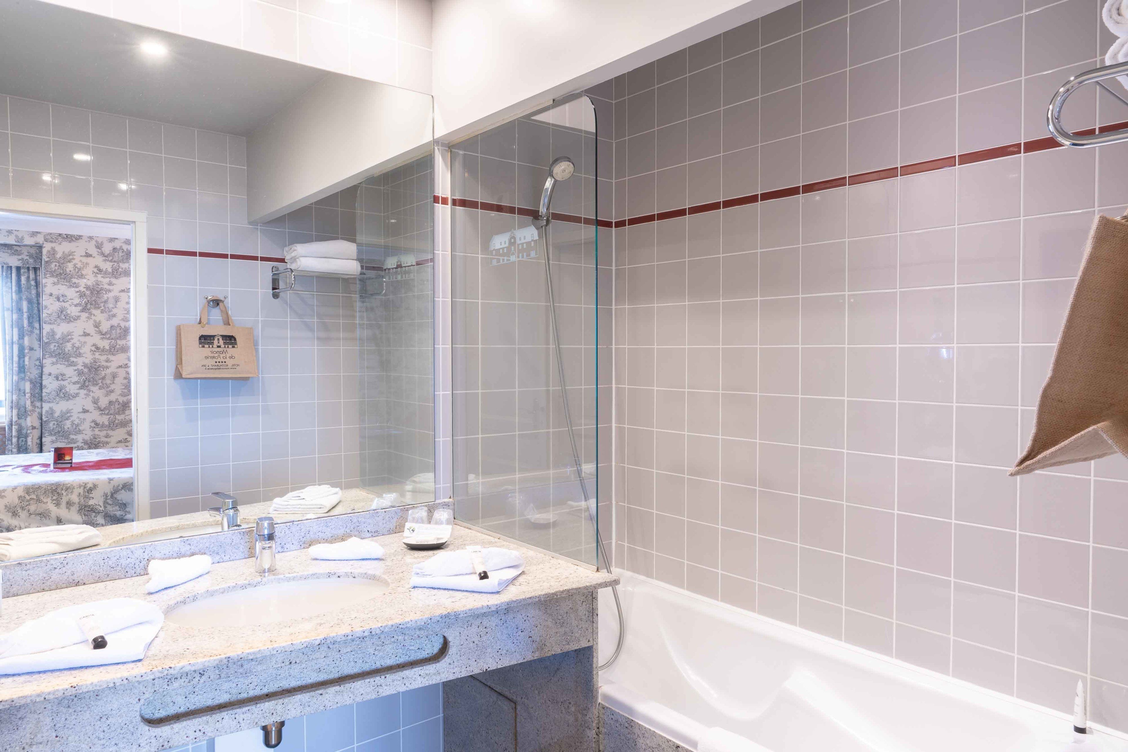 Un baño moderno con ducha envuelta en vidrio, lavamanos de mármol y bañera.
