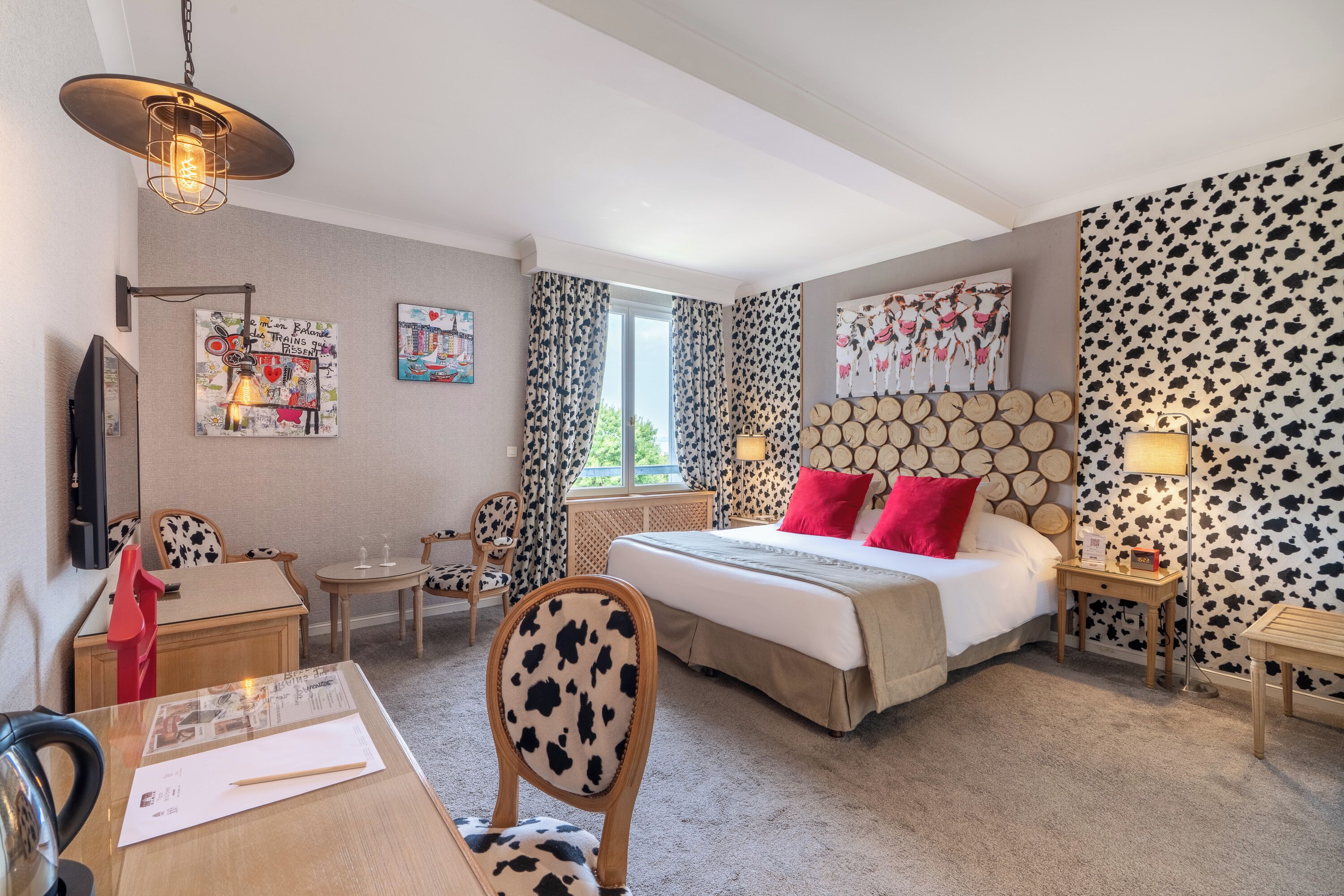 Ein Hotelzimmer mit Bett, Schreibtisch, Stuhl, Fernseher und Fenster.