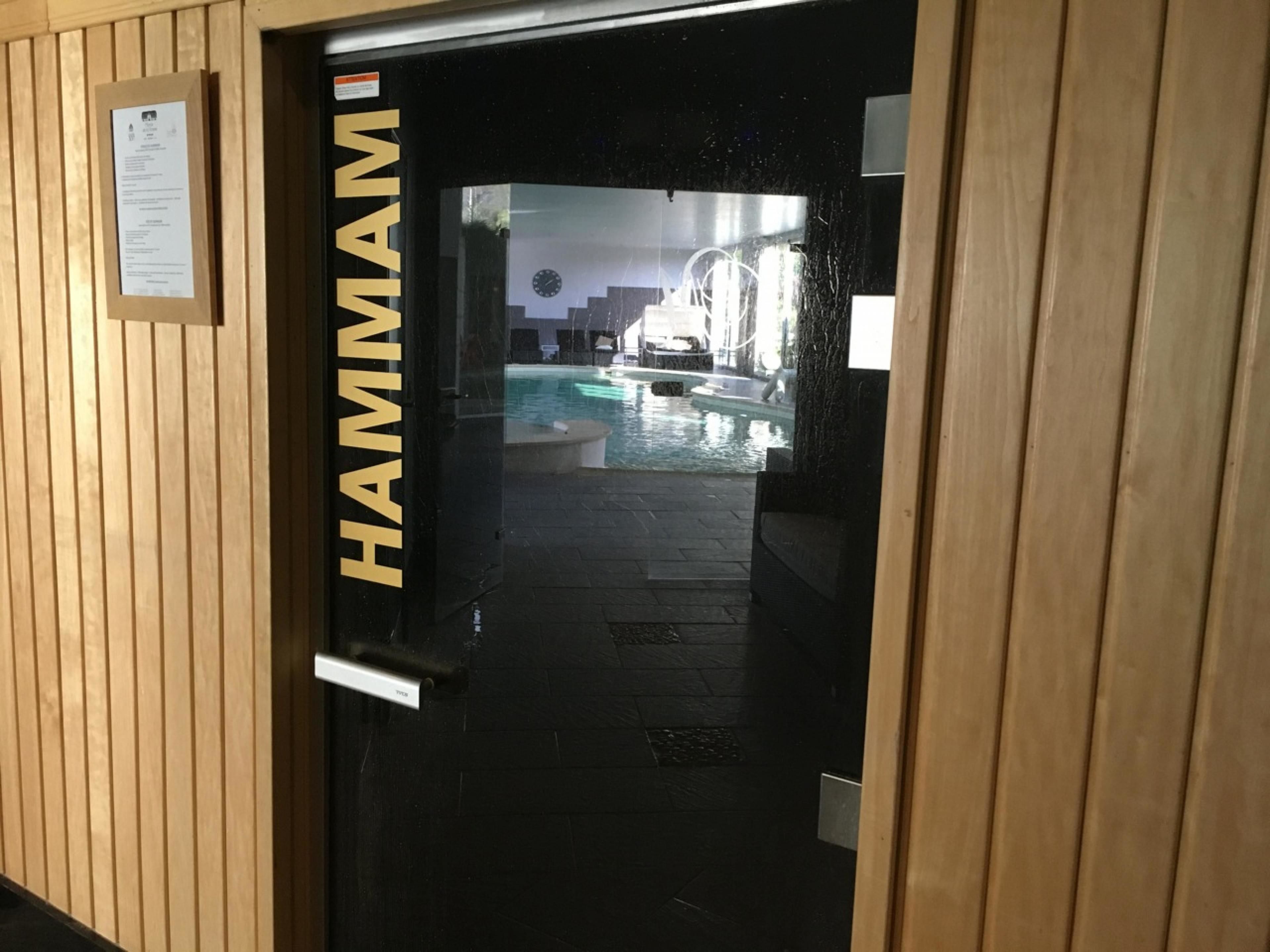 Una puerta de madera con la palabra "HAMMAM" que indica una zona de sauna.