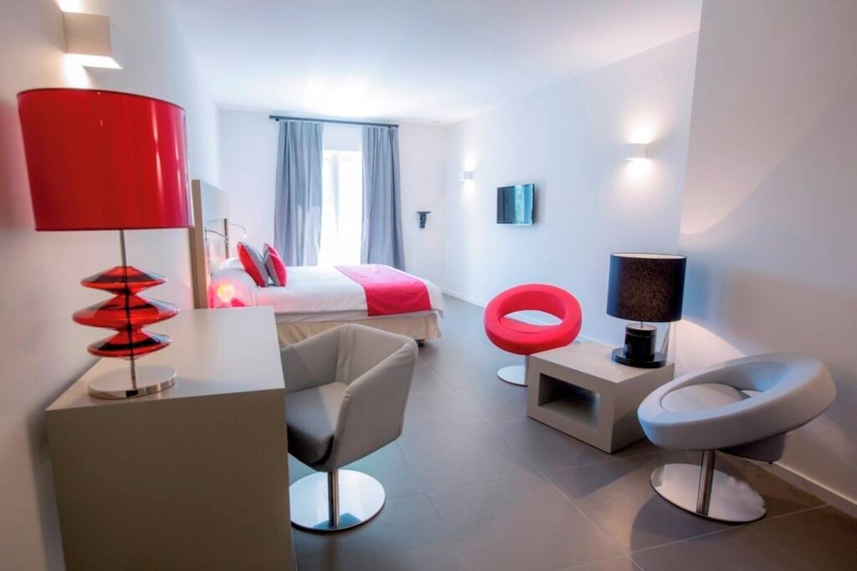 Ein modernes Hotelzimmer mit Bett, Schreibtisch, Stuhl, Fernseher und Lampe.