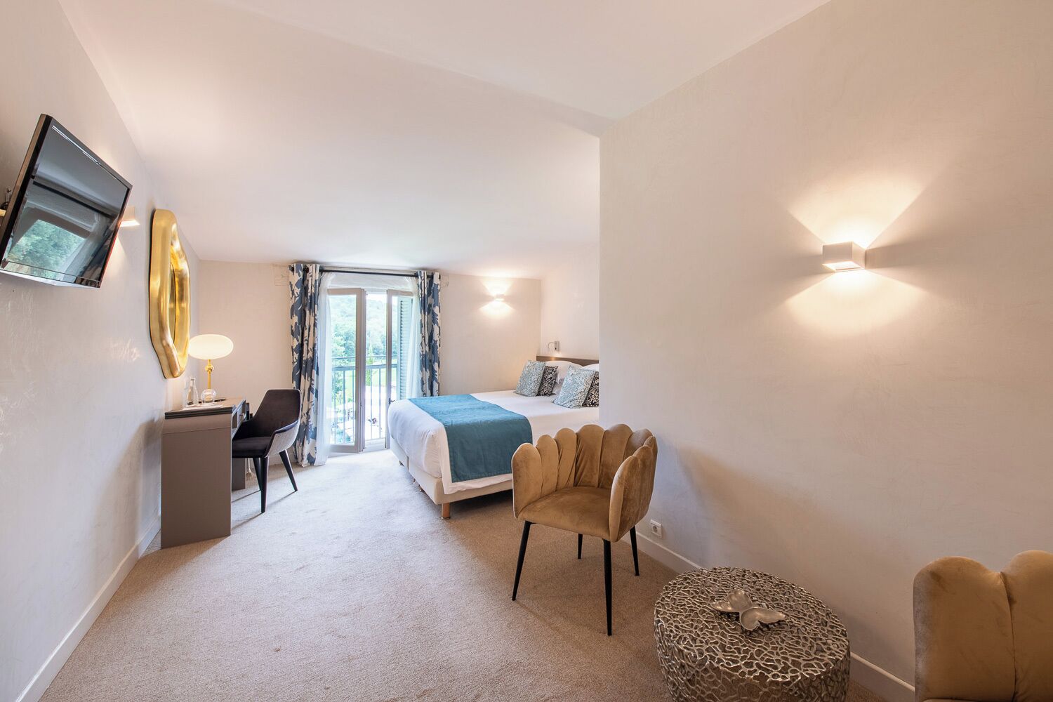 Une chambre d’hôtel moderne équipée d’un lit, d’un bureau, d’une chaise et d’un pouf rond.