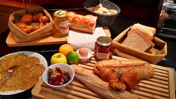 Un buffet de petit-déjeuner proposant un assortiment de pains, de viennoiseries, de fruits et de condiments.
