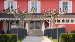 Een rood gebouw met witte luiken, een stenen muur en een pad dat naar de ingang leidt.