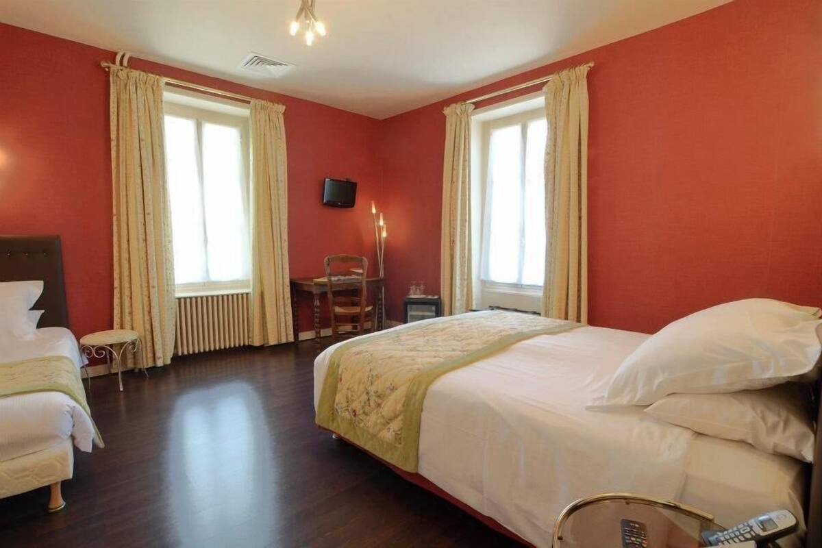 A hotel room with two beds, a desk, a chair, a television, and a lamp.