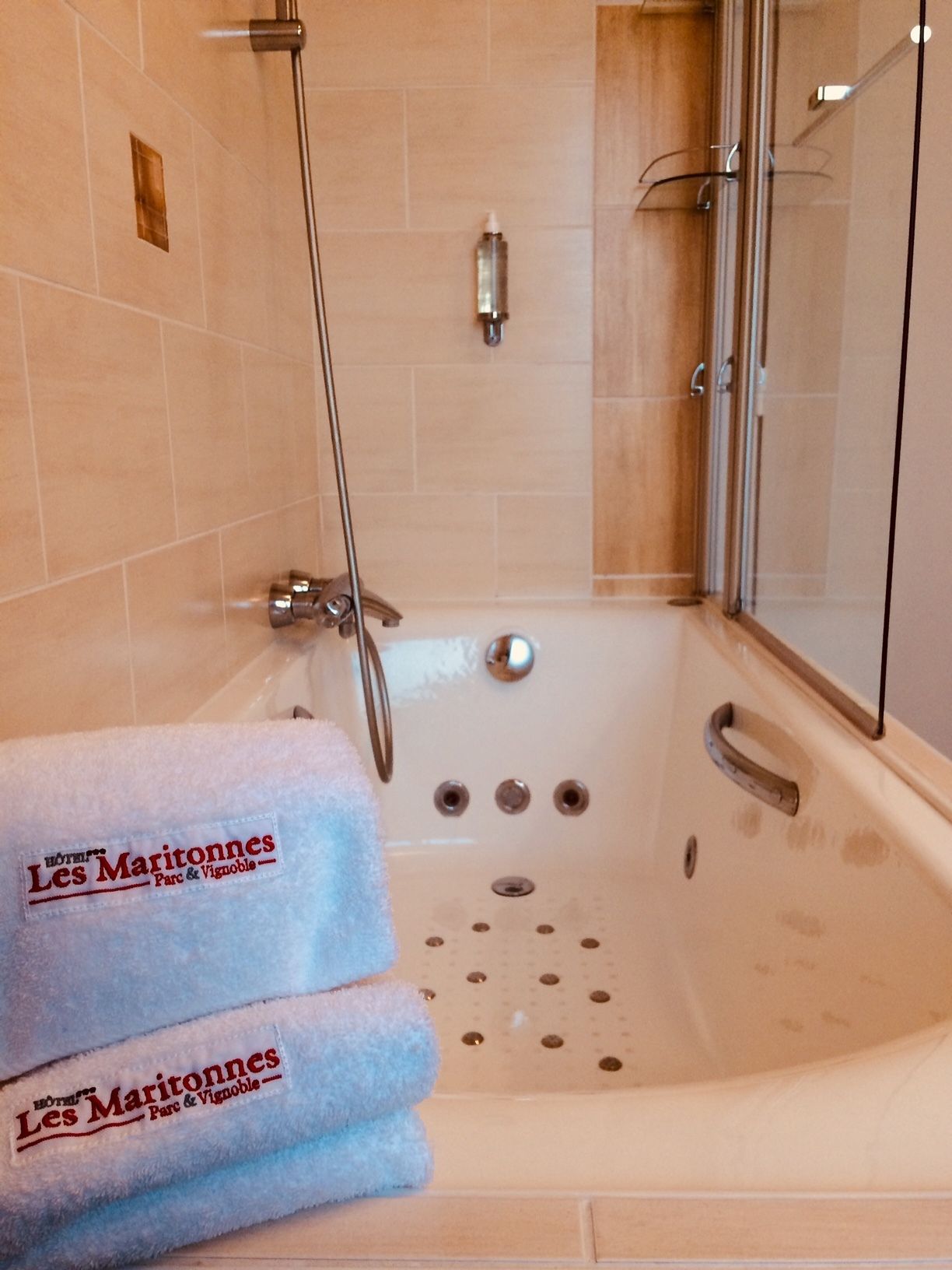 Un bagno con vasca, doccia e due asciugamani con il nome dell'hotel.