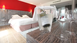 Een hotelkamer met een bed, een tafel met een glas water en twee wijnglazen.