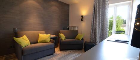 A modern living room with two sofas, a small table, and a TV.