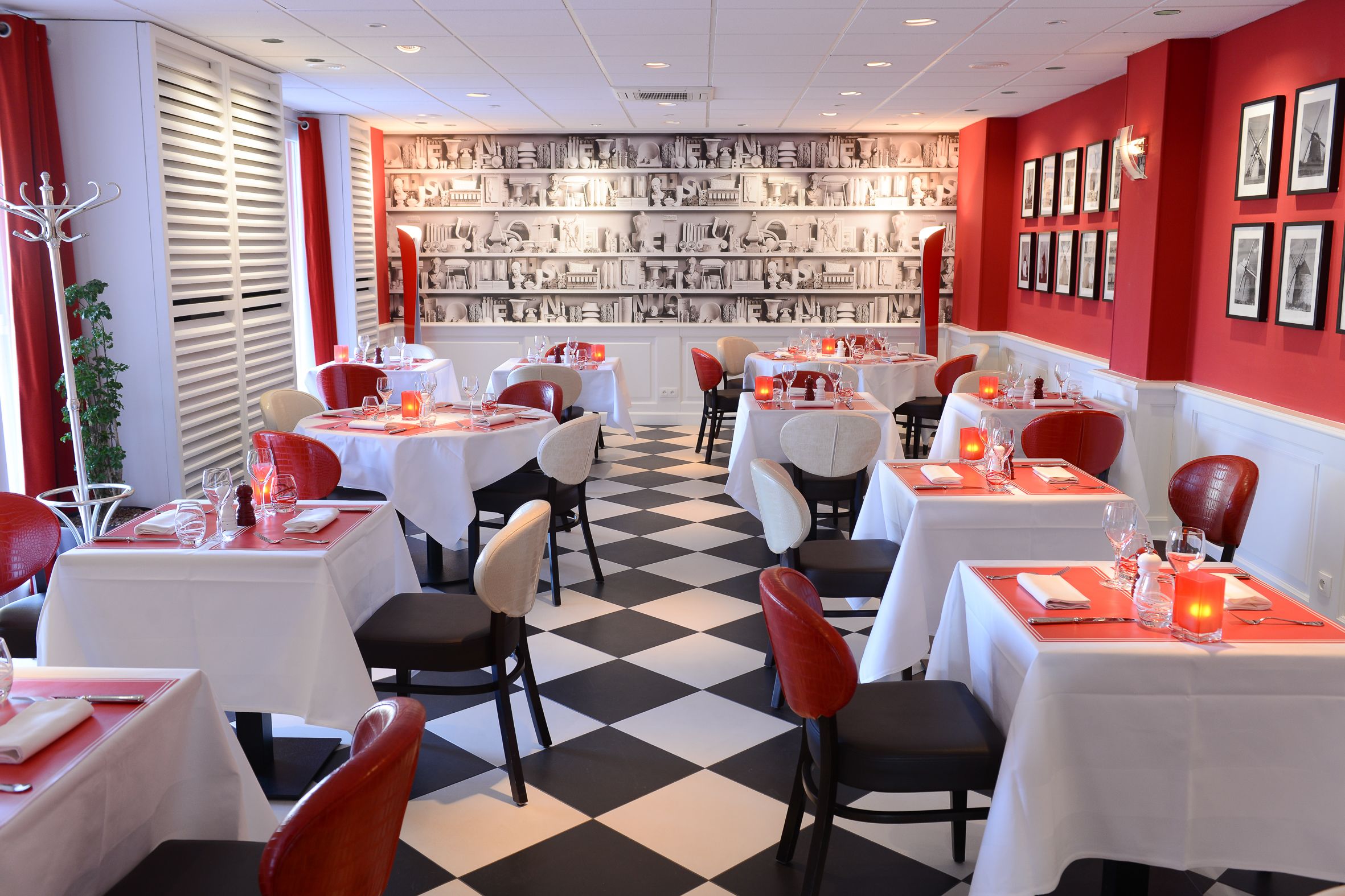 Un restaurante con mesas dispuestas para comer, un fondo con pared decorada y cortinas rojas.