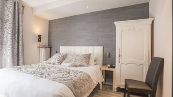 A modern bedroom with a large bed, a white wardrobe, and a chair.