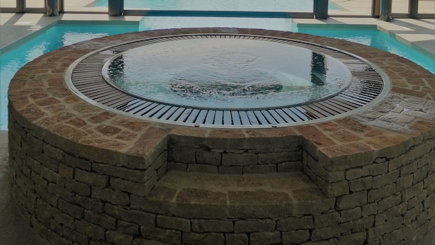 Een wellnessruimte met een jacuzzi, een zwembad en uitzicht op een wijngaard.