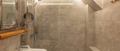A modern bathroom with a sink, mirror, shower, and a bench.