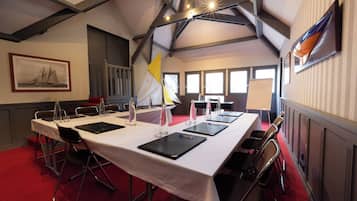 Un salón de conferencias con una larga mesa, sillas y un mantel blanco.