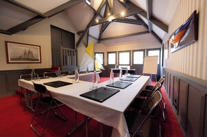 Une salle de conférence avec une longue table, des chaises et une nappe blanche.