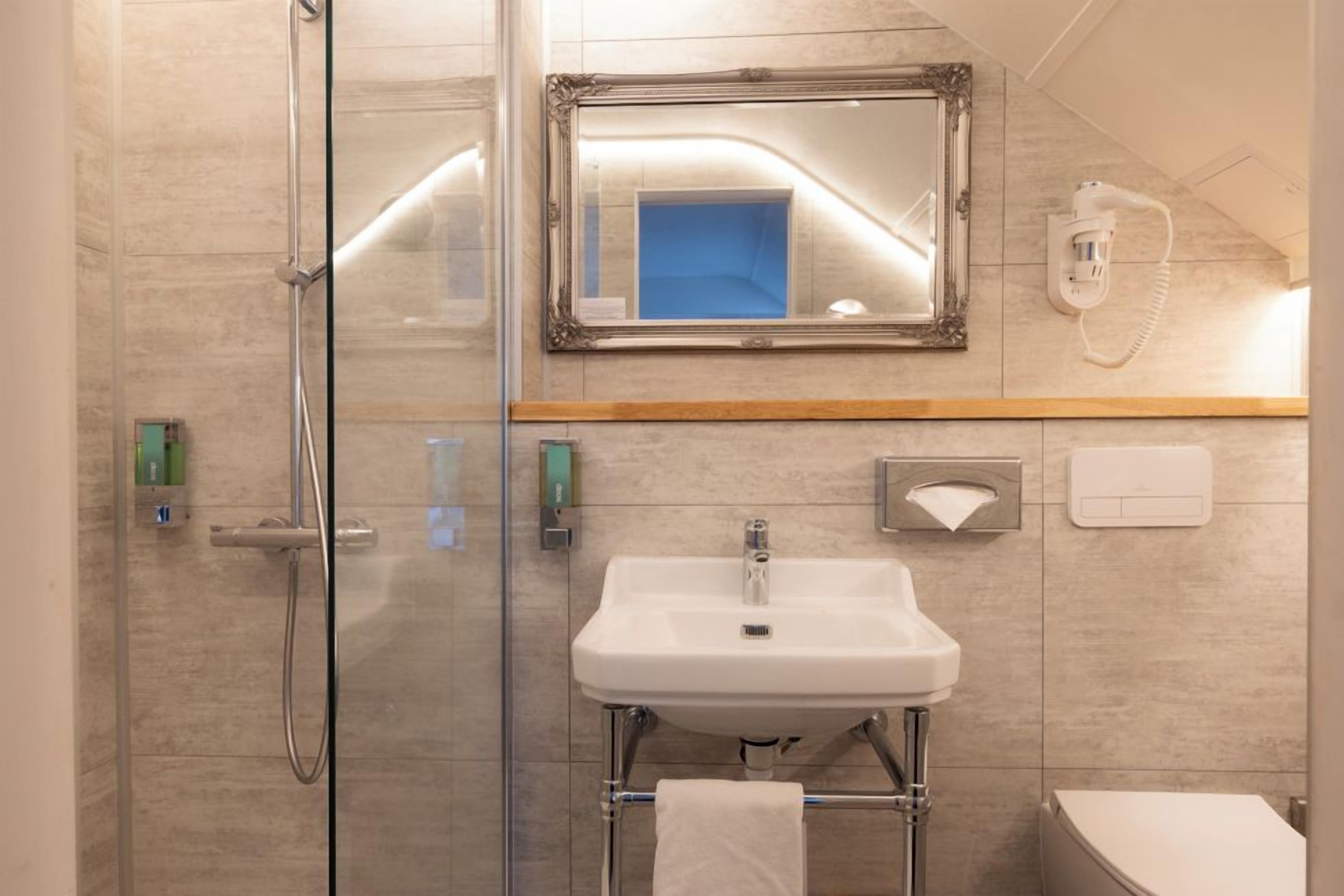 Une salle de bain moderne avec une douche à parois de verre, un lavabo blanc et un miroir au-dessus.