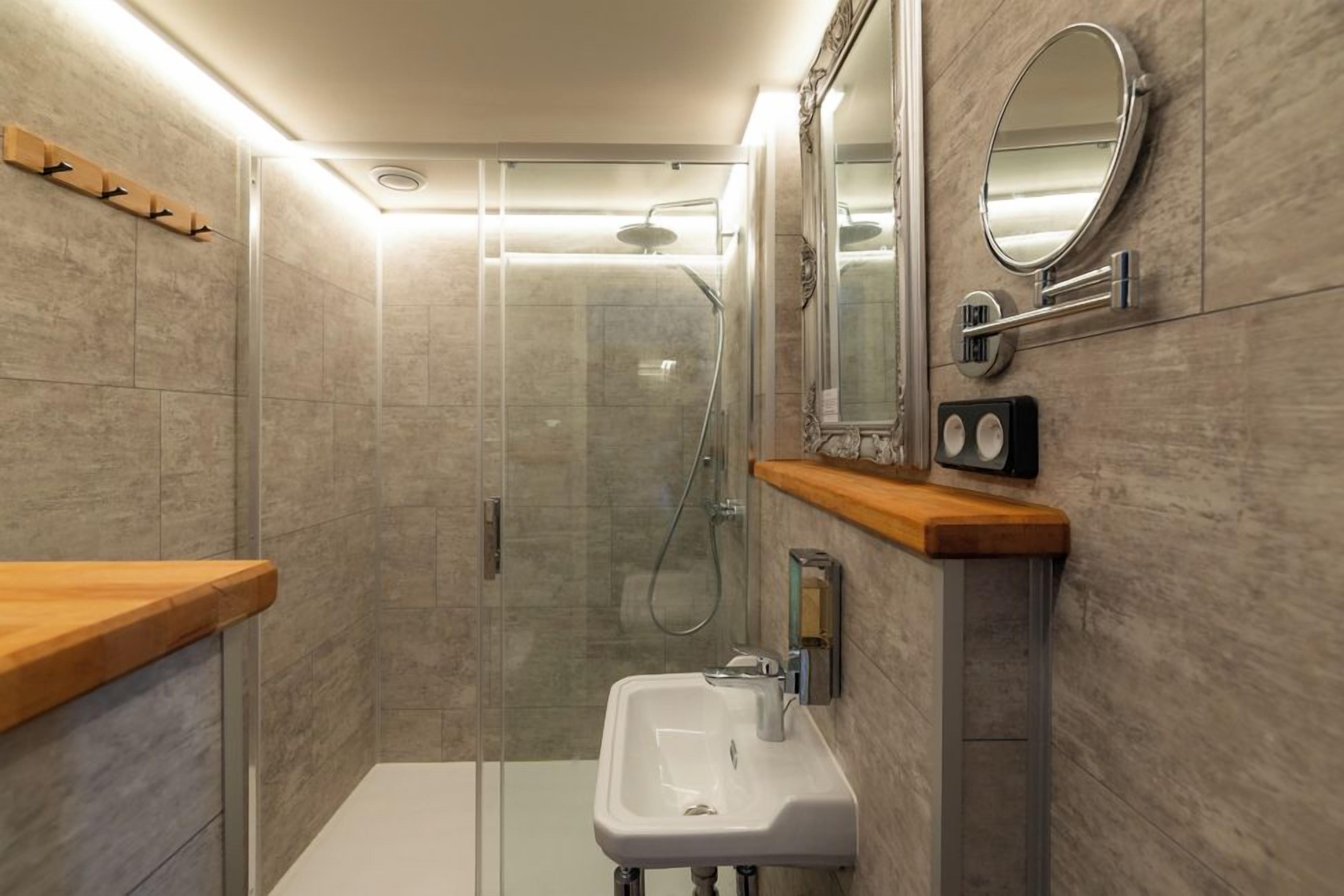 Une salle de bain moderne avec une douche à parois de verre, un lavabo blanc et un plan de toilette en bois.