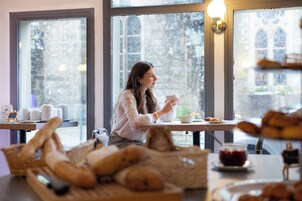 Une personne assise à une table, devant une tasse, des pâtisseries et un bol.