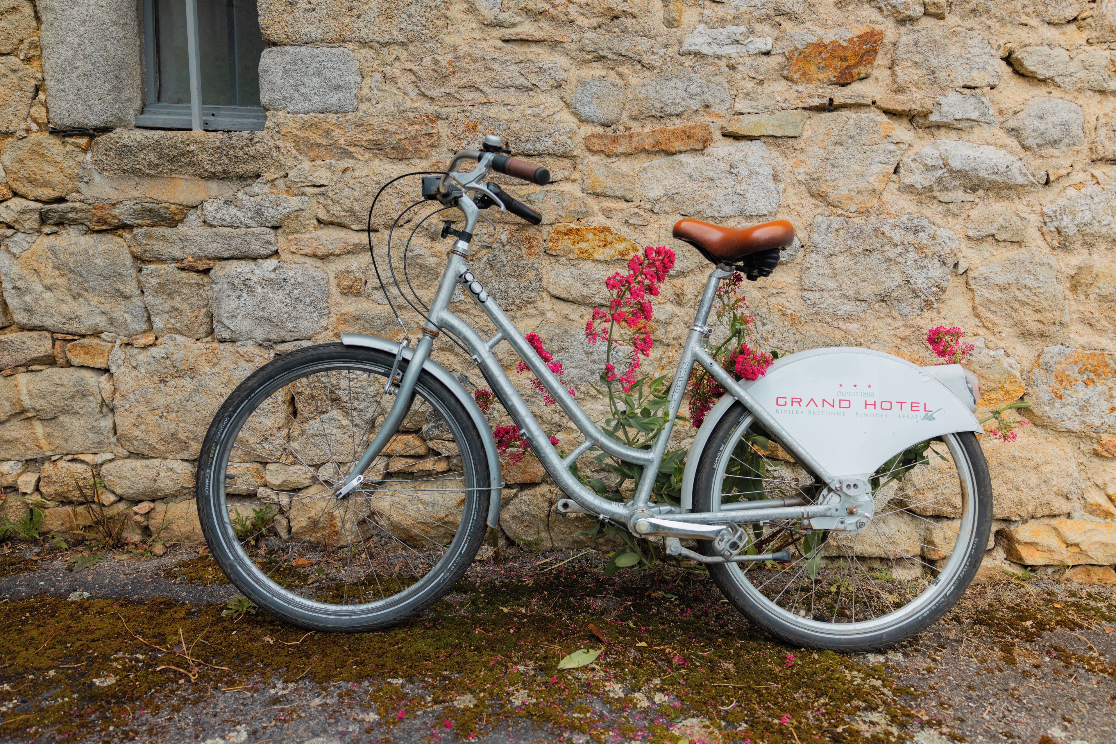 A vintage bicycle with a white seat and a metal frame, parked against a stone wall.