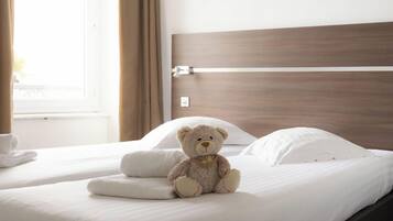 Un lit avec un ours en peluche, des oreillers blancs et une tête de lit en bois.
