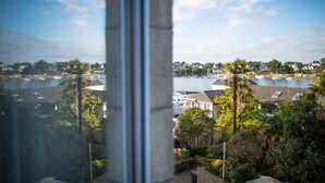 Vista costeira com um porto de iates, edifícios residenciais e palmeiras.