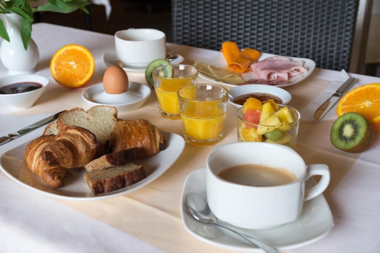 A breakfast setting with croissants, orange juice, fruit, and coffee on a table.