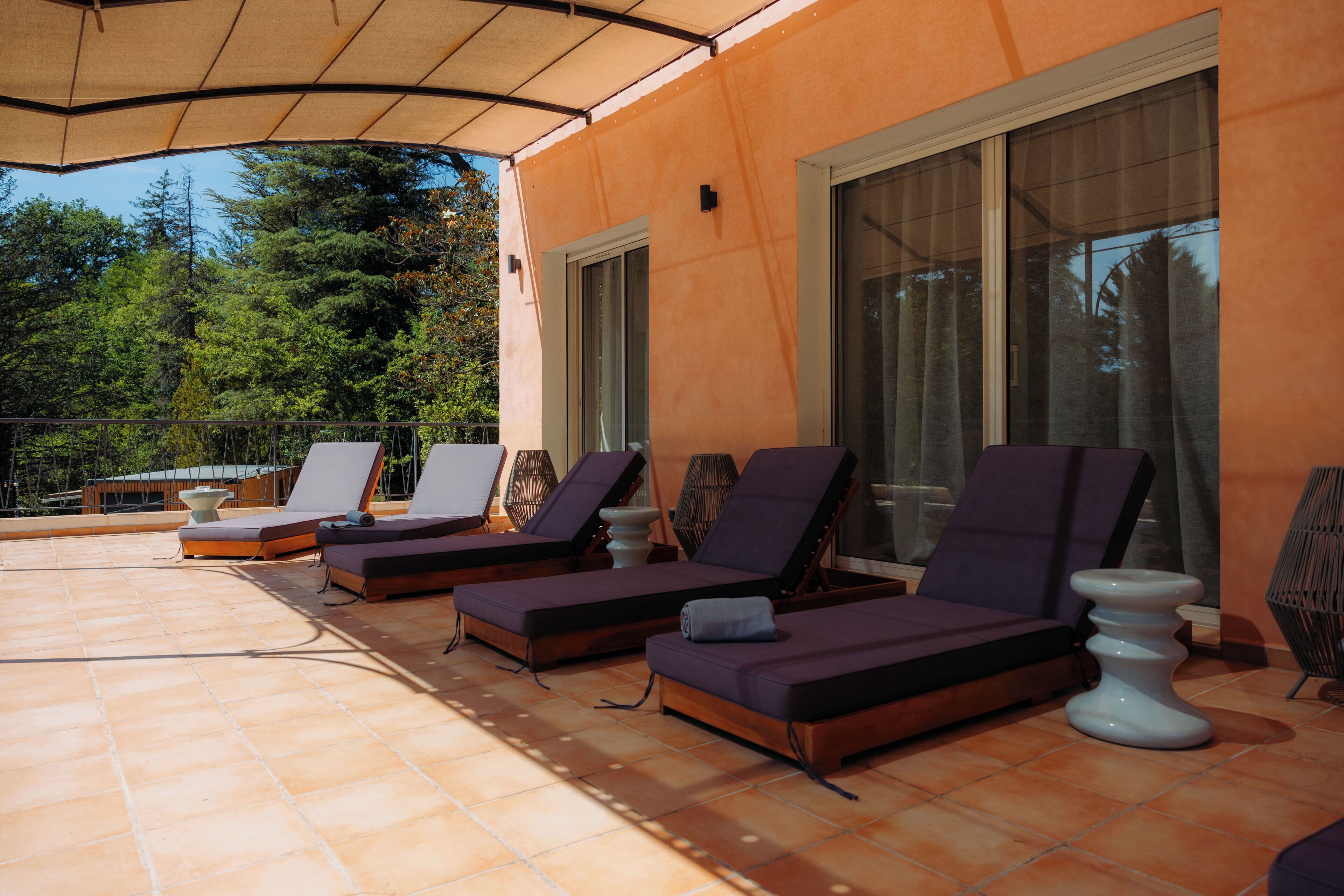 A sunlit outdoor seating area with lounge chairs and a tiled floor.