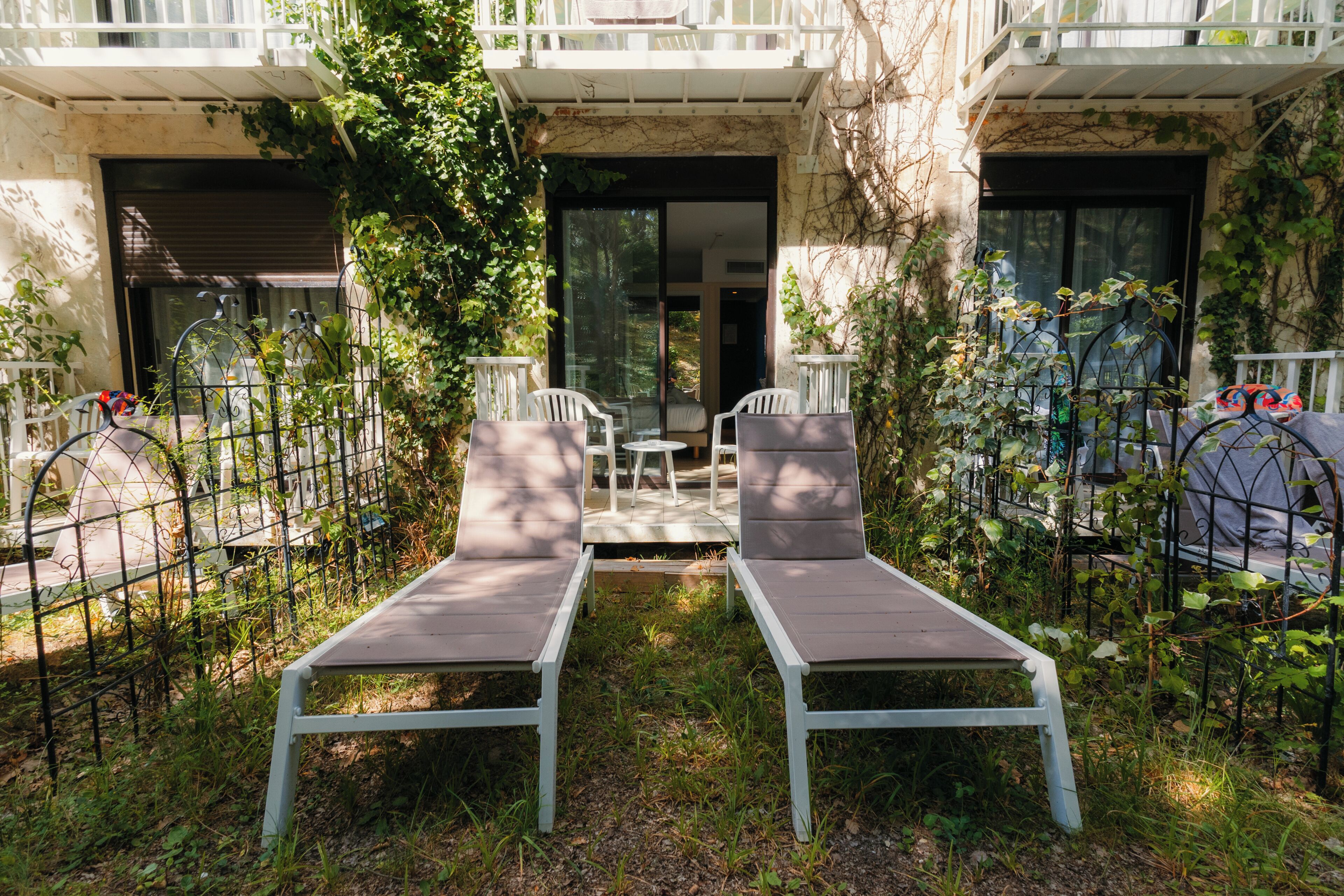 A courtyard with two lounge chairs, a table, and chairs.