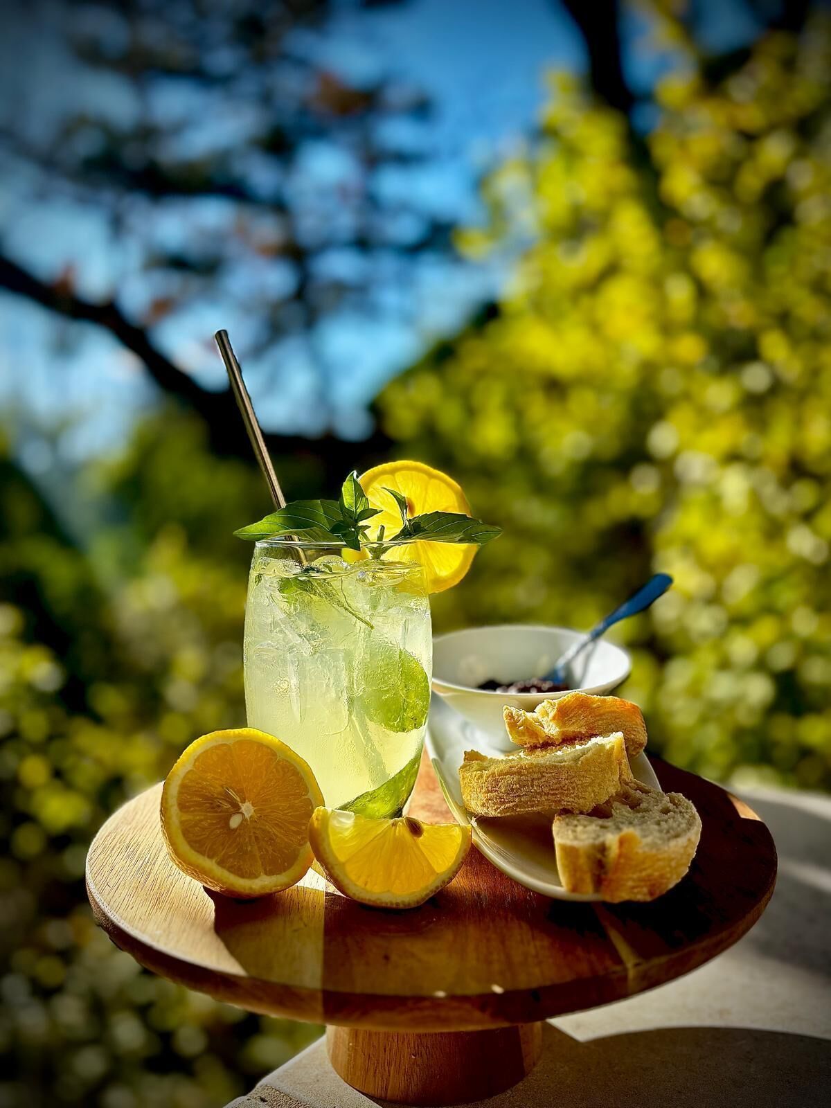 Un verre de limonade, garni de rondelles de citron et de quelques feuilles de menthe, posé sur un plateau en bois.