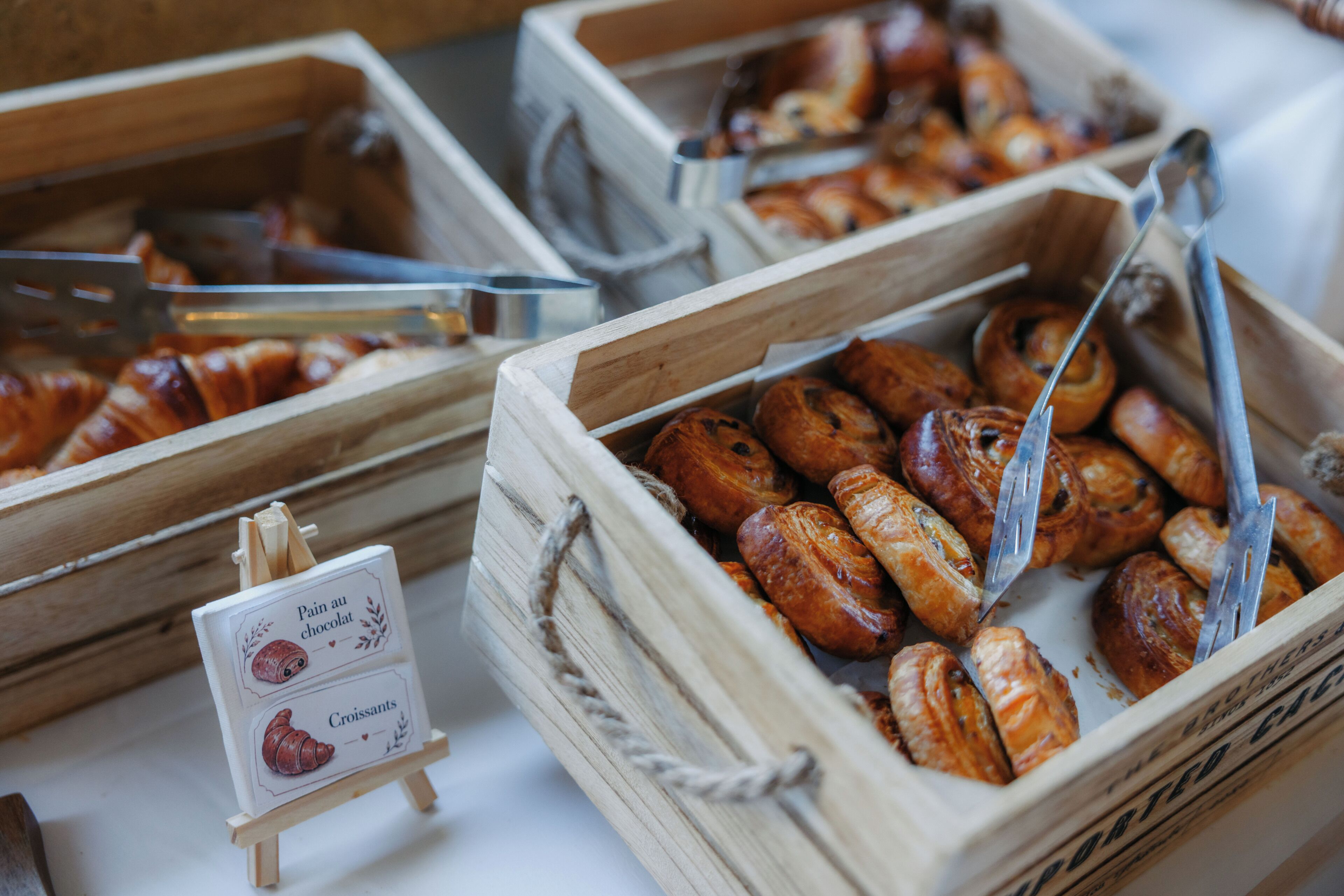 Wooden display cases with pastries and a sign indicating chocolate croissants.
