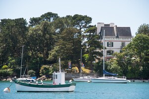 Un puerto deportivo con varias embarcaciones amarradas, un edificio con la leyenda "Villa Tri Men" al fondo y un paisaje de árboles.