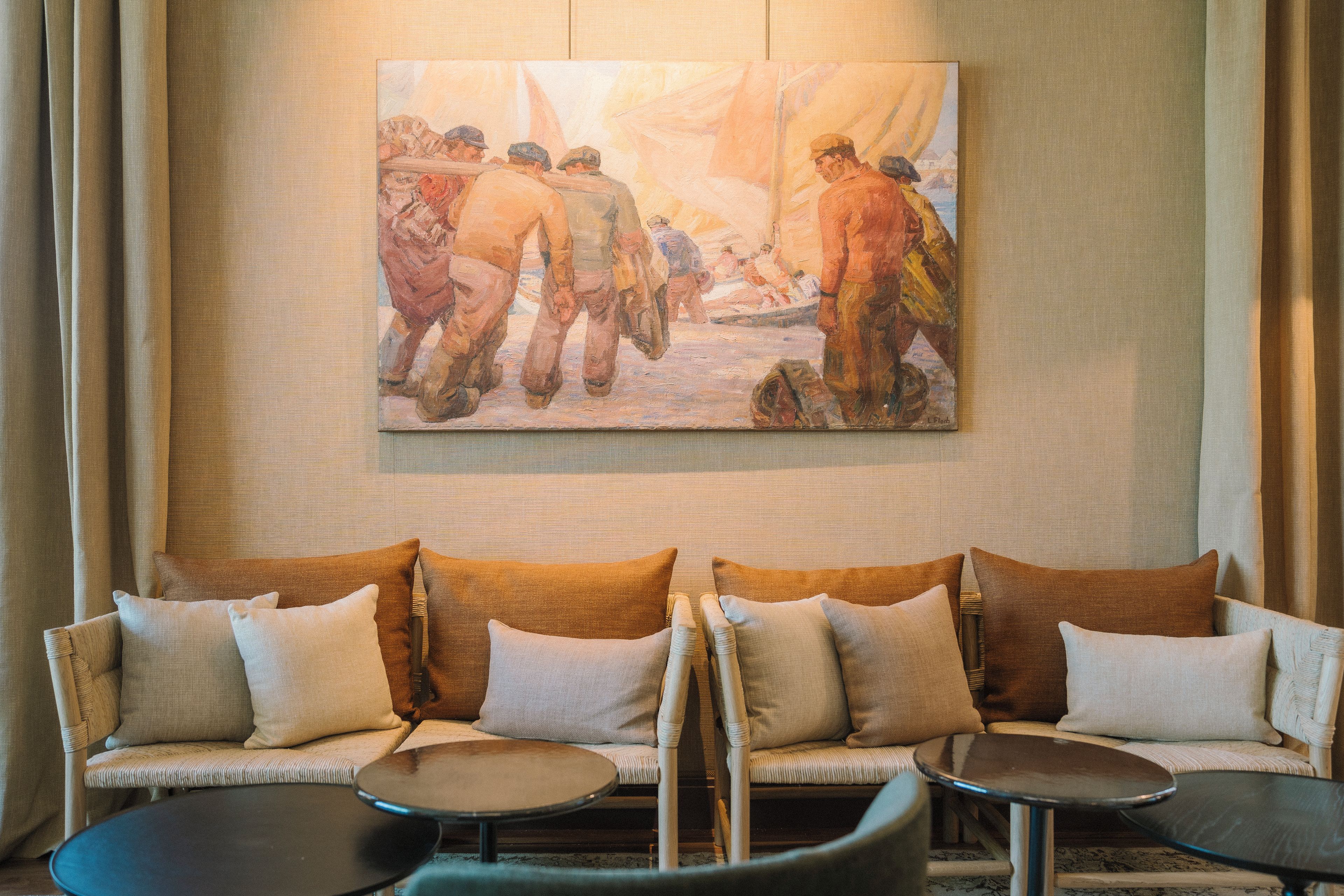 A hotel lobby with a large painting, a sofa set, and two side tables.