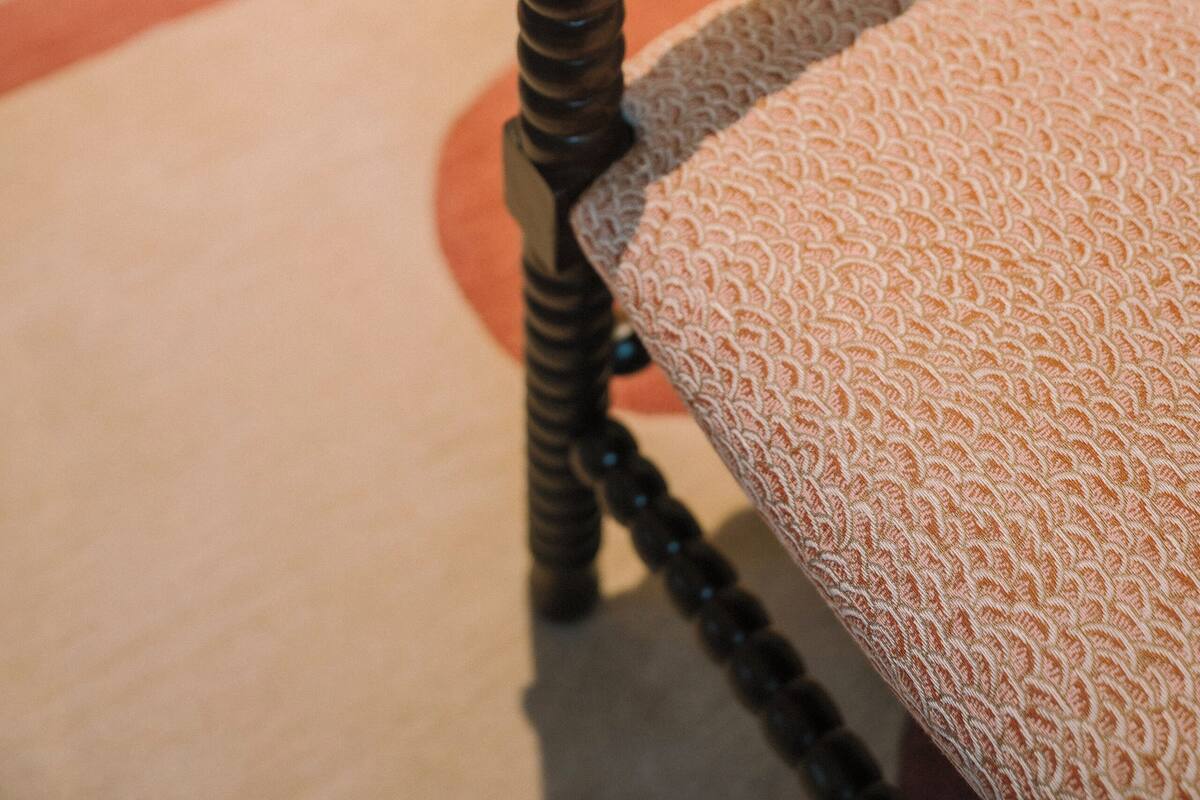 A close-up of a wooden chair with a patterned cushion.