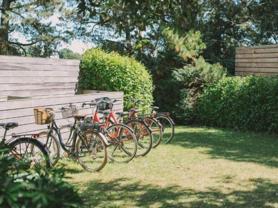 A wooden deck with bicycles parked, surrounded by greenery and a wooden fence.
