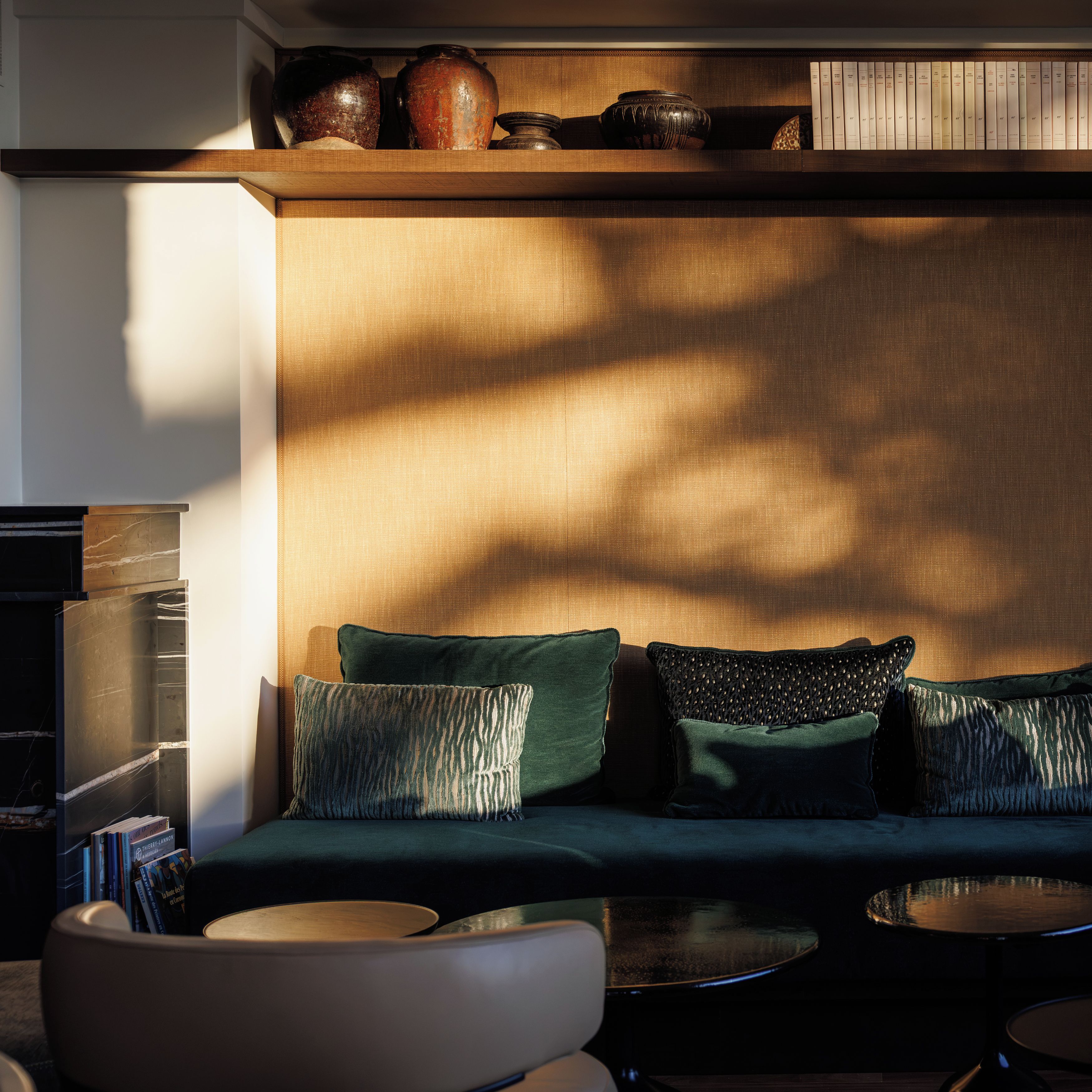 Una sala moderna con un sofá, dos mesitas auxiliares y una estantería con libros y objetos decorativos.