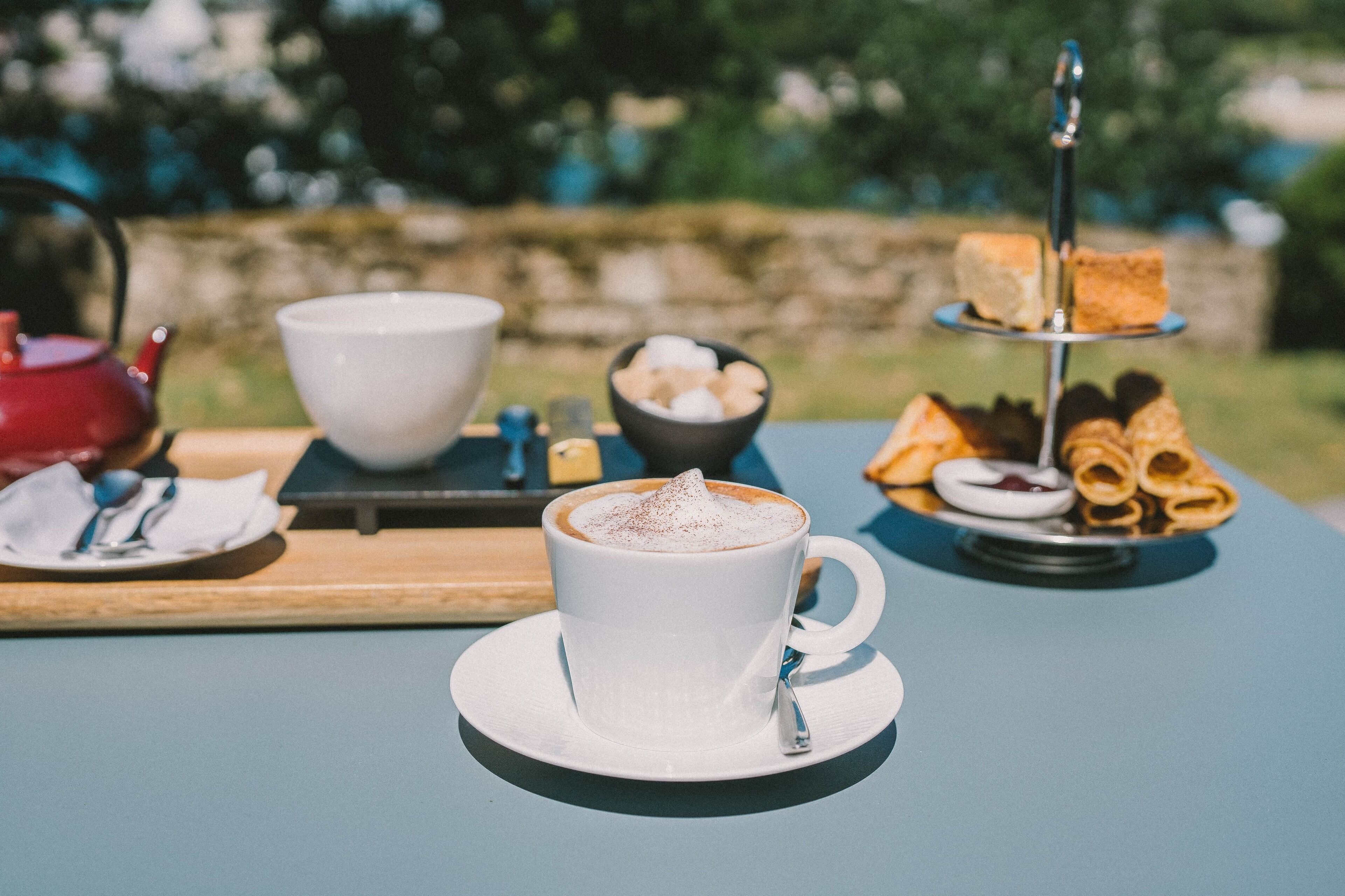 Une table avec une tasse de café, un bol de guimauves et une assiette de pâtisseries.