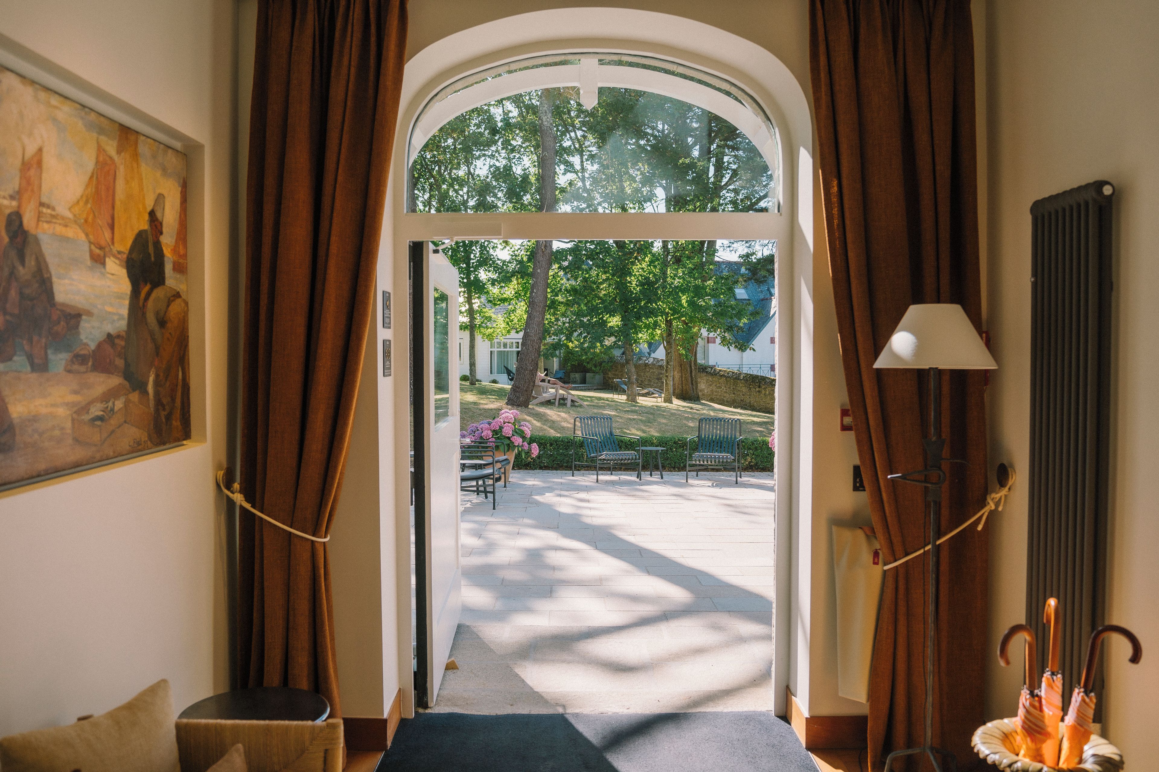 An entrance with a view of a park, a bench, and outdoor seating.