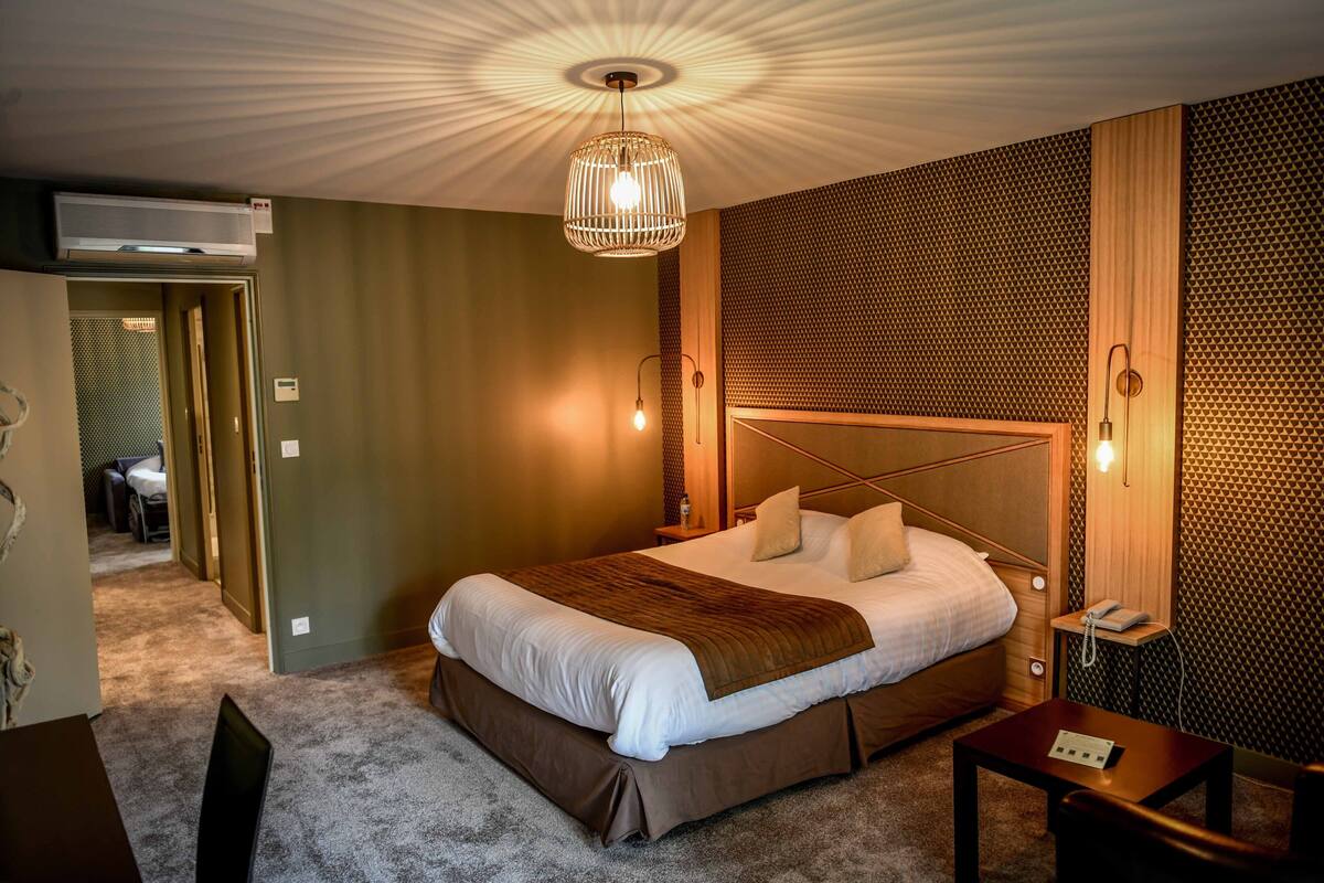Una habitación de hotel con una cama grande, una mesita de noche, una lámpara y un aplique de techo.