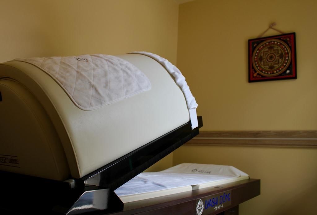 A fax machine on a desk with a wall-mounted decorative item in the background.