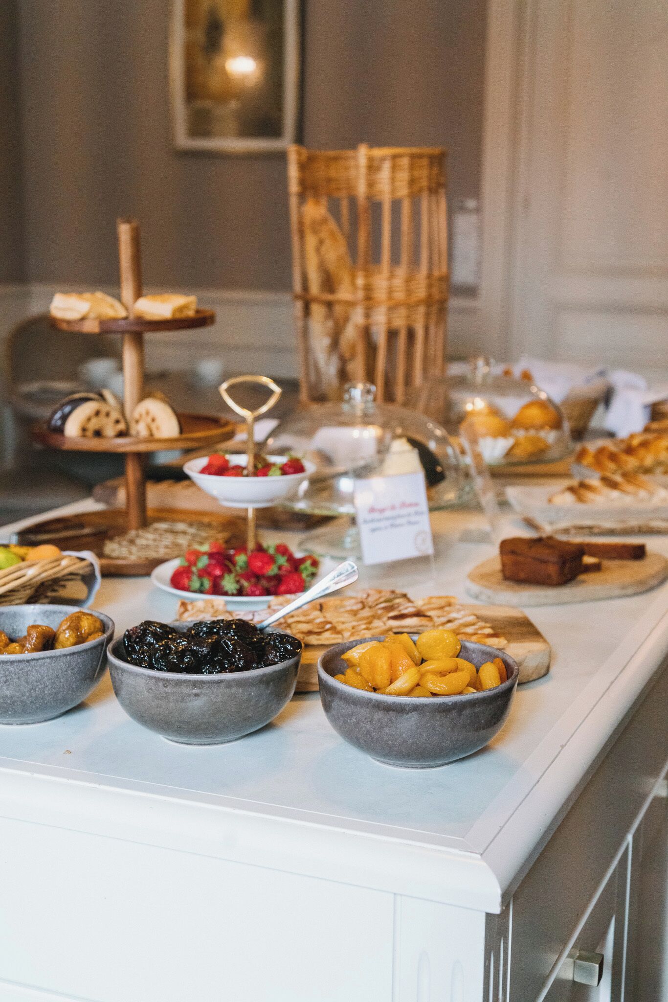 Un buffet proposant une variété d’aliments, notamment des fruits, des pâtisseries, ainsi qu’un panneau indiquant les boissons disponibles.