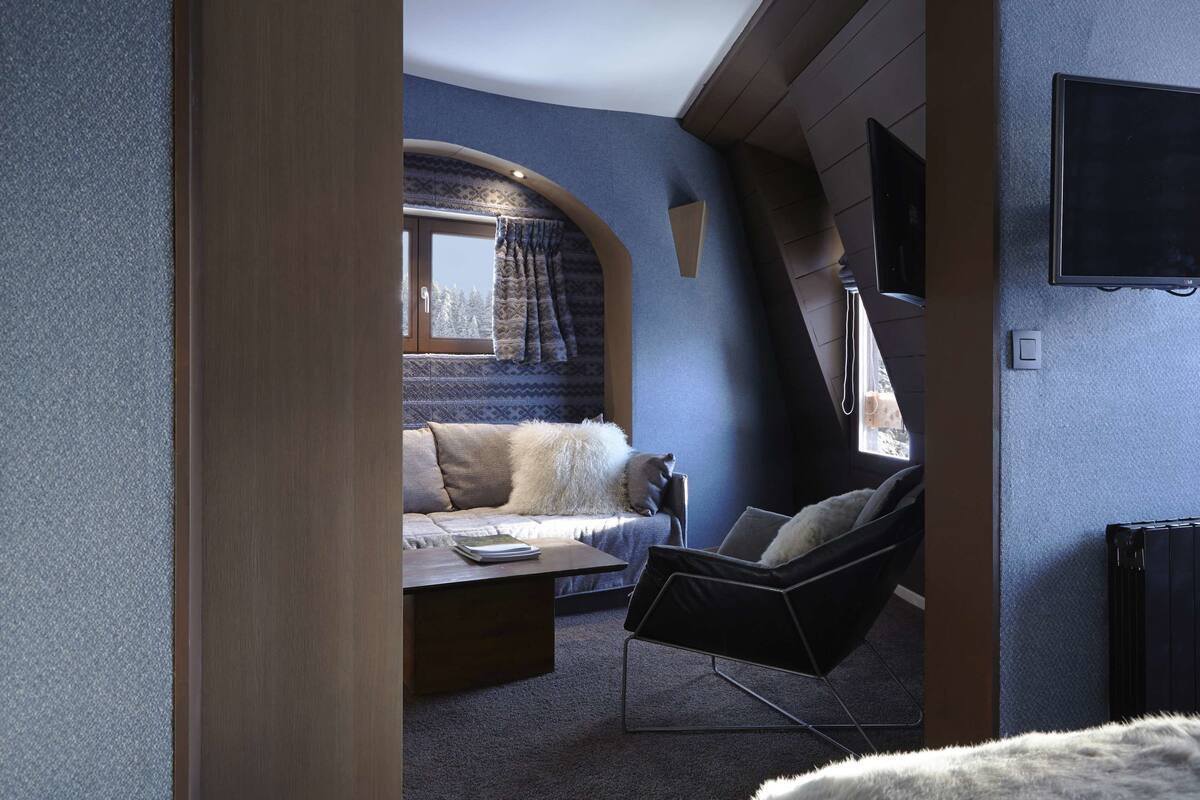 Habitación compacta con sofá, sillón, mesa y ventana con cortinas.