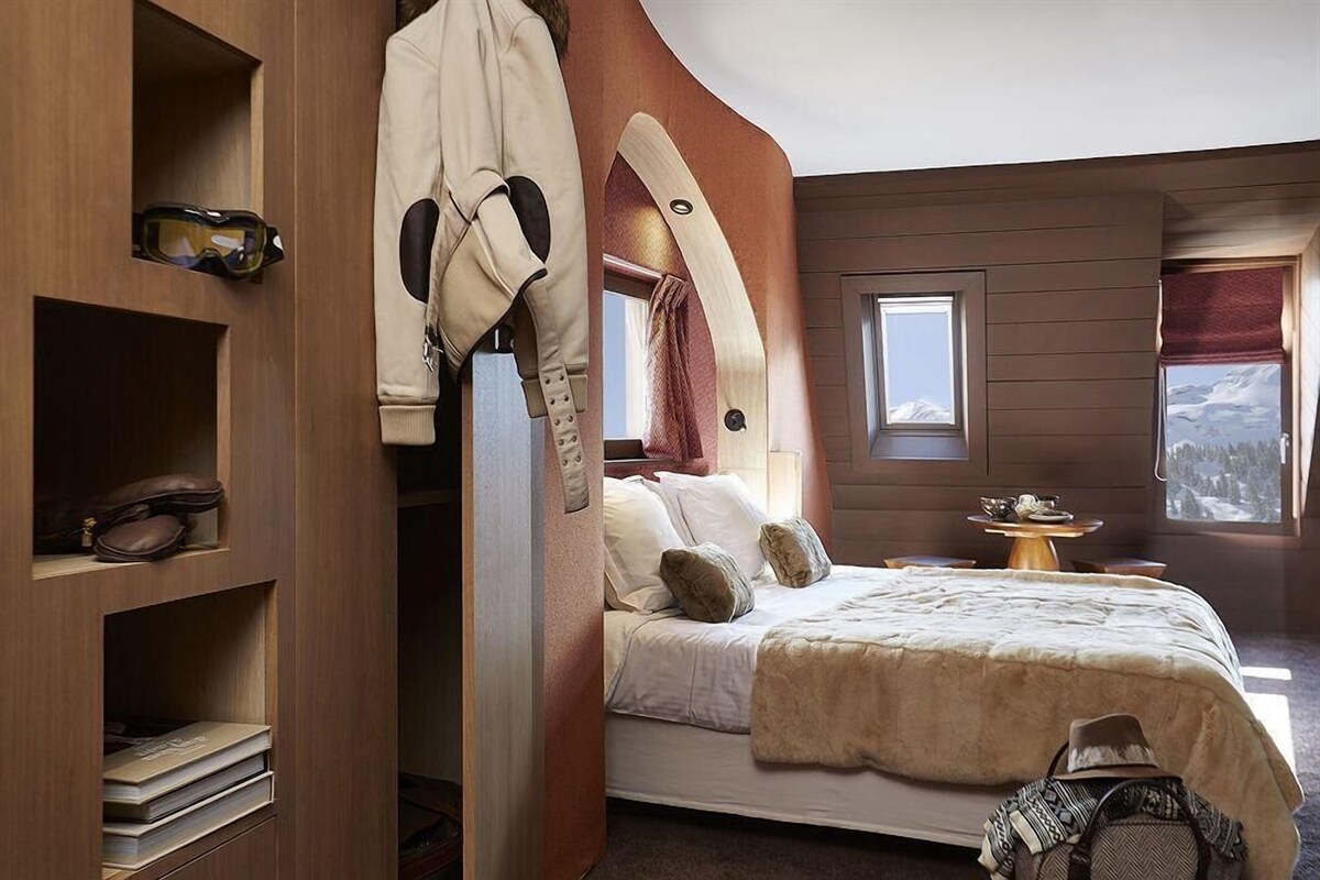 Une chambre à coucher avec un lit, une armoire, une petite table et une fenêtre donnant sur un beau paysage.