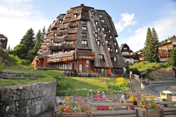 A multi-story building with balconies, a restaurant, and a stone wall.