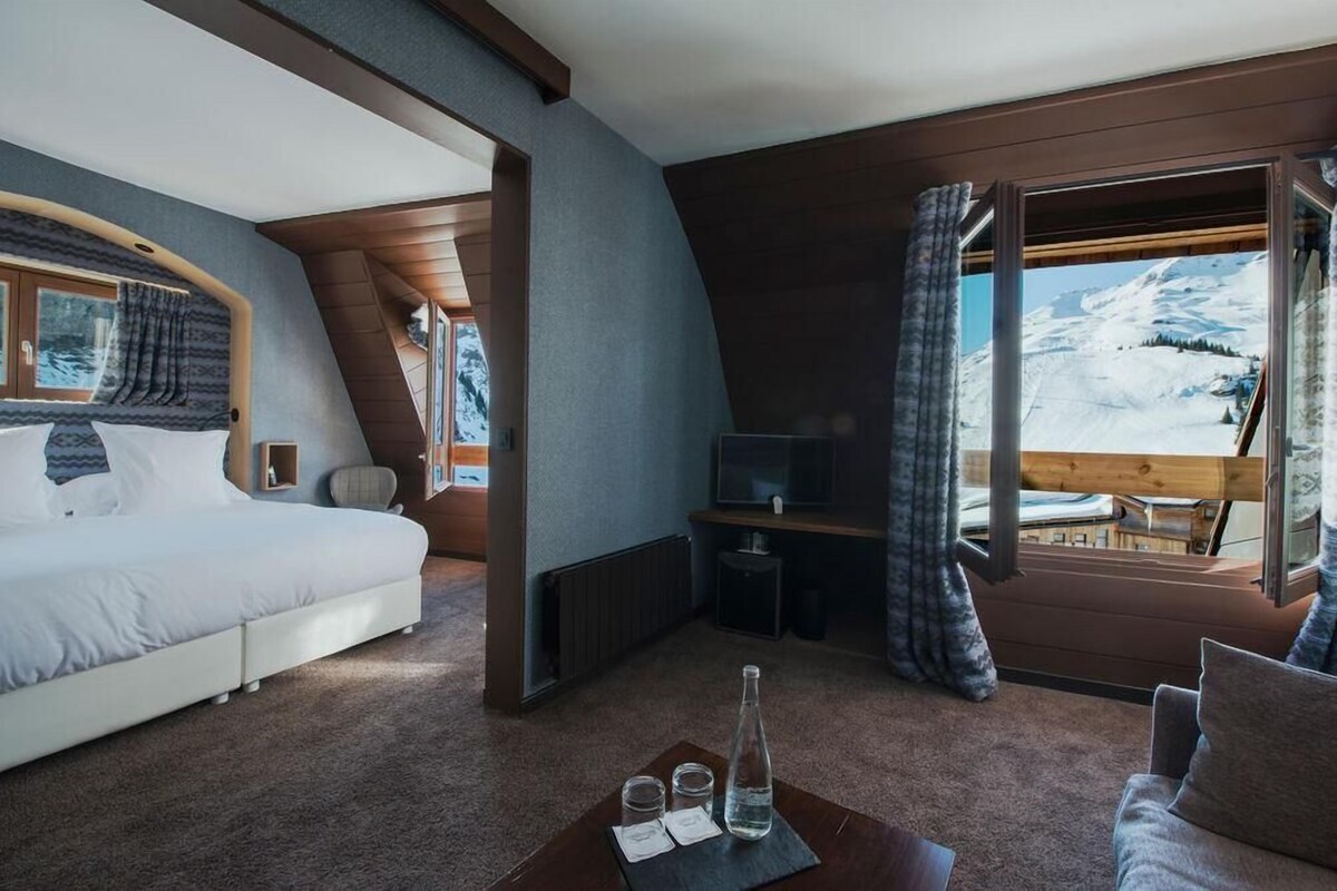Une pièce confortable avec un lit, un bureau et une vue sur un paysage enneigé.