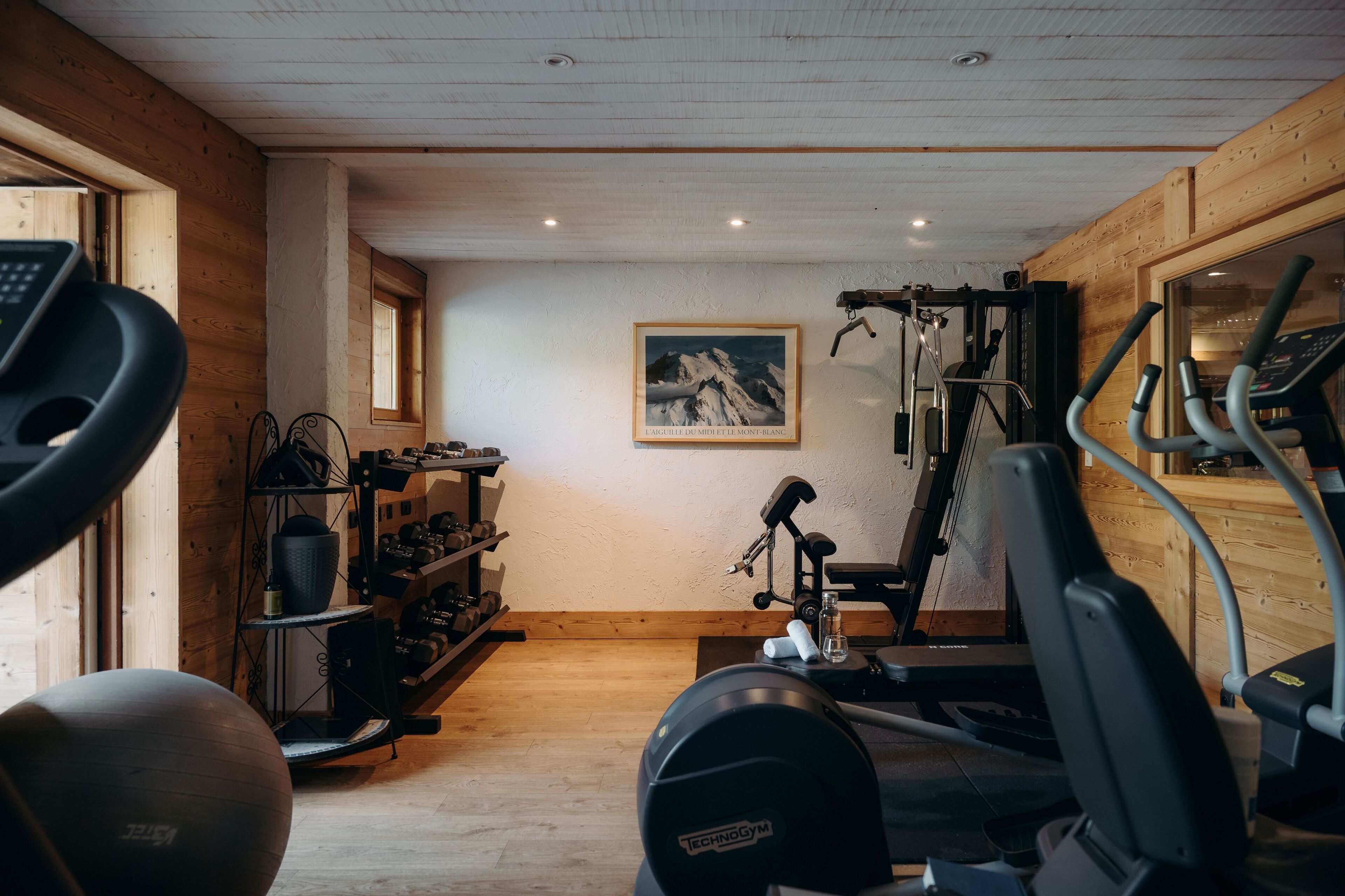 Une salle de sport équipée de matériel d’exercice, d’un tapis de course et d’un porte-haltères fixé au mur.