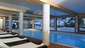 Zona de piscina con sillas de descanso y vista a un paisaje nevado.