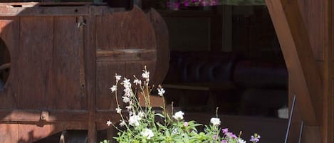 A wooden pergola with a hanging flower basket and a potted plant with various flowers.