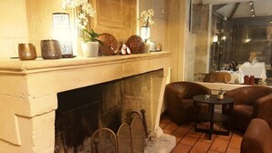 A cozy room with a fireplace, leather seating, and a view of a dining area. - Hôtel Belesso (Fontvieille)