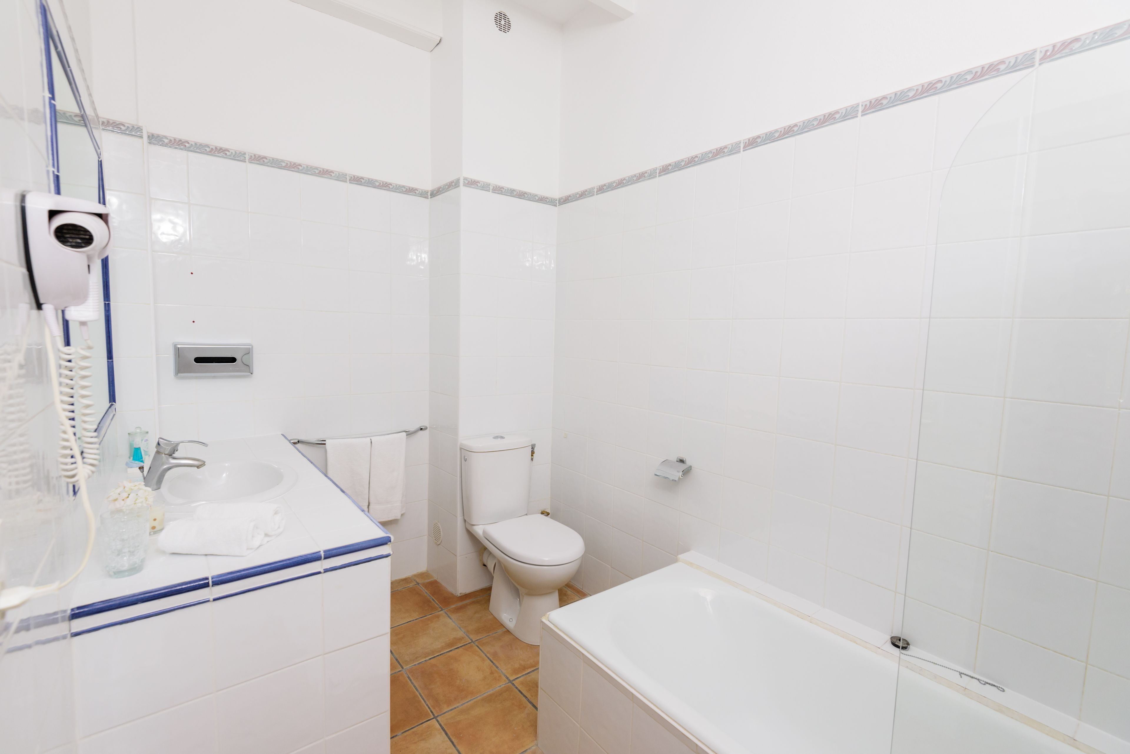 Un baño con lavamanos, inodoro y bañera blancos.
